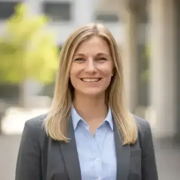 Smiling woman with blonde hair in a grey blazer and light blue collared shirt.